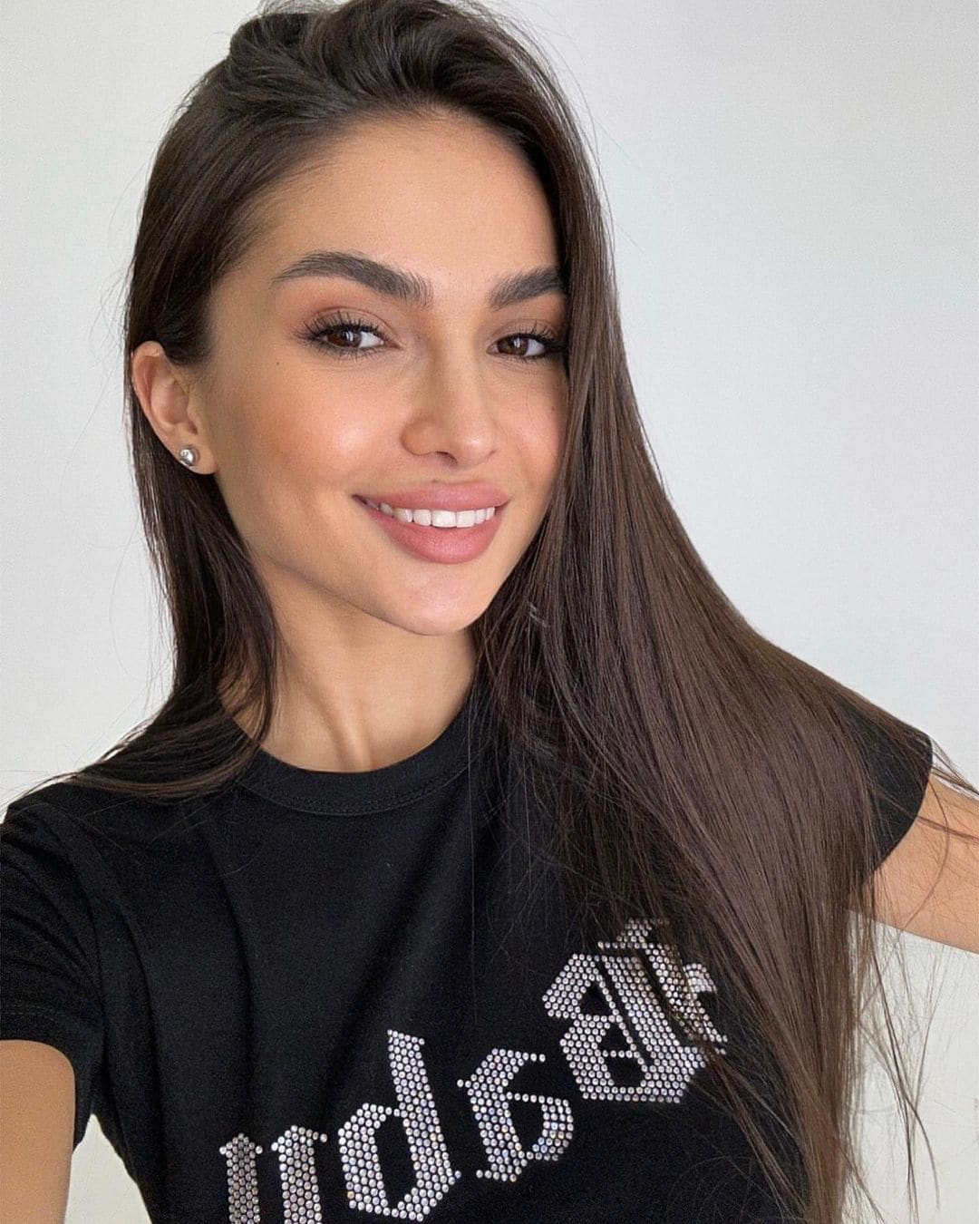Tanya smiles in a black rhinestone t-shirt against a plain light background.